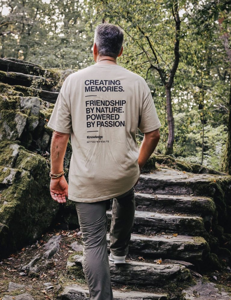 Person trägt ein T-Shirt mit Text, geht eine Treppe in der Natur hinauf.